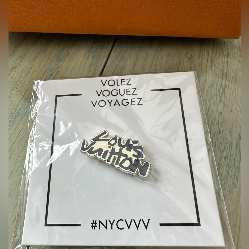 Louis Vuitton volez voguez voyagez exhibit pin